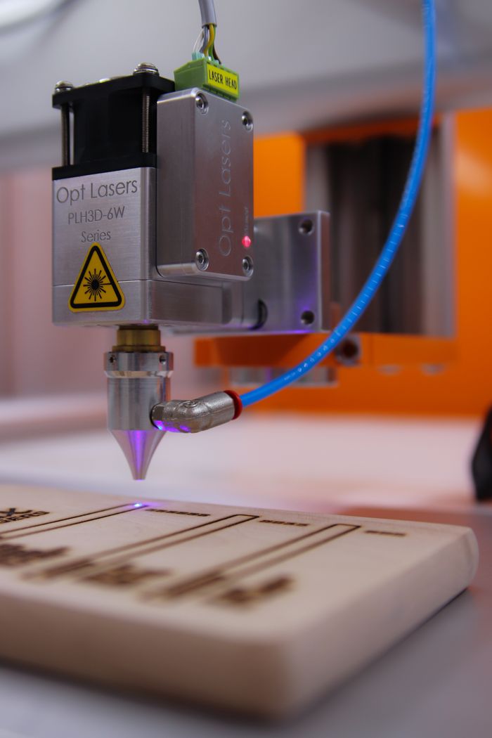 Home High-tech laser engraving machine working on wooden surface.