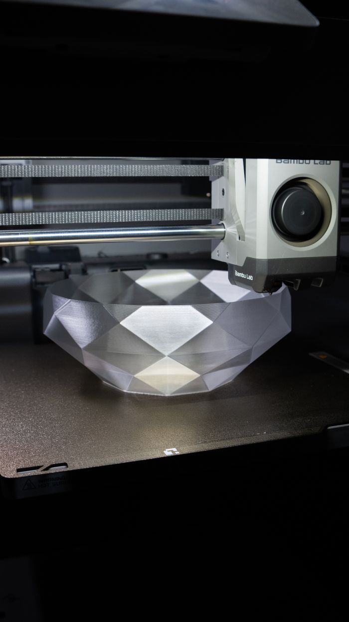 About A 3D printer creating a geometric crystal-like bowl in a modern setup.